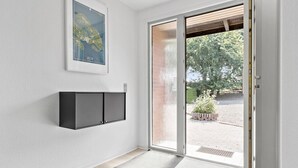 A hallway with a sliding glass door leading to an outdoor area, a framed map on the wall, and a black cabinet.
