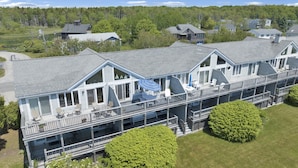 A multi-story hotel with a covered outdoor area featuring a table and chairs, a blue umbrella, and a view of a lake. - Ocean views on Gooch's Beach! (Kennebunk)