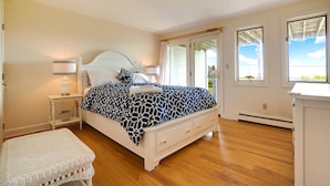 A bedroom with a bed, bedside tables, a lamp, a window, and a view of the outside. - Ocean views on Gooch's Beach! (Kennebunk)
