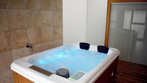 A hot tub with a control panel, wooden paneling, and tiled walls. - Un Lujo a tu Alcance (Salamanca)