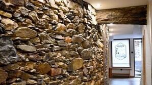 A stone wall with a rustic interior, a wooden beam ceiling, and a sign with text. - Un Lujo a tu Alcance (Salamanca)