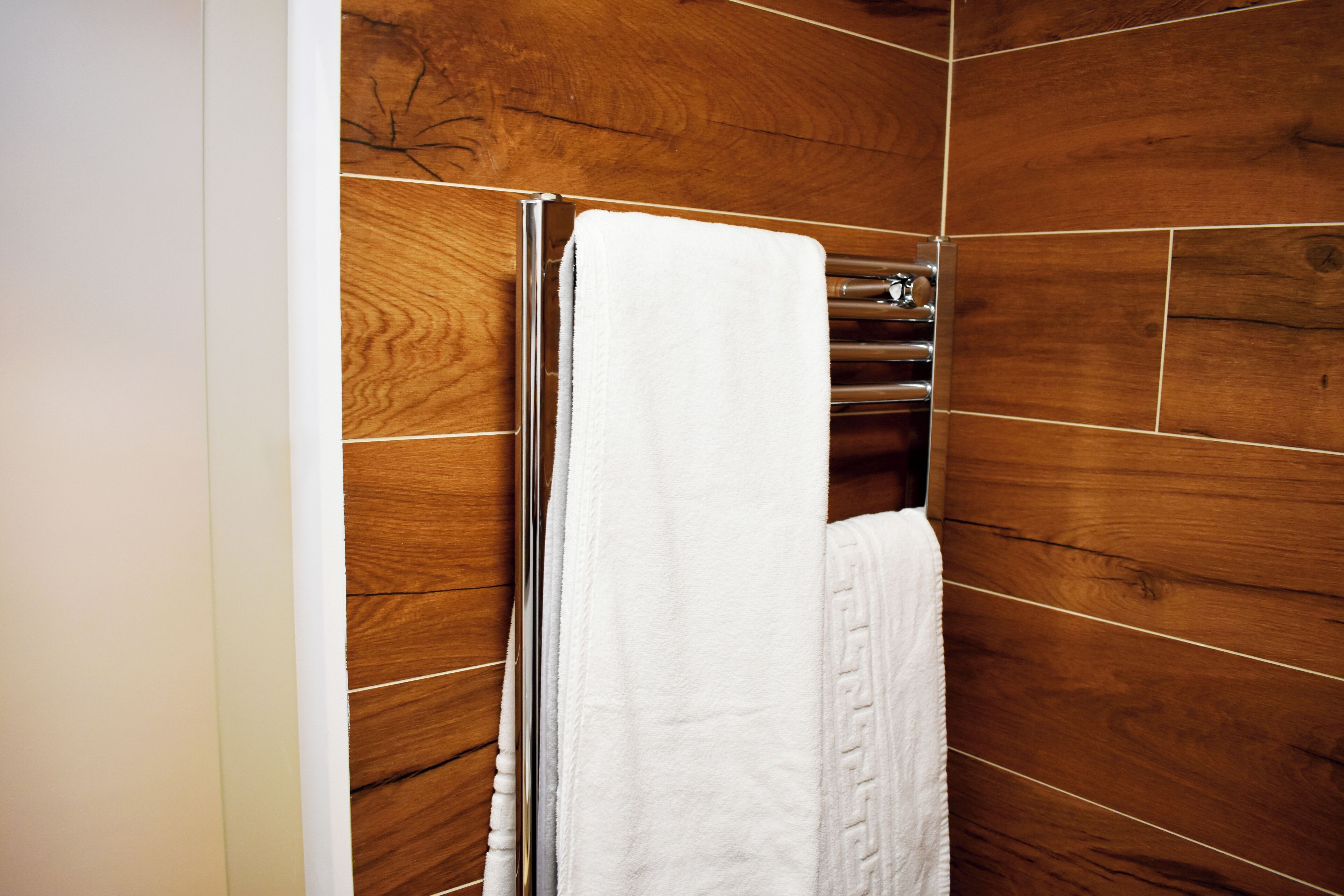 Un bagno con pareti in legno e un asciugamano bianco appeso a un portasciugamani cromato.