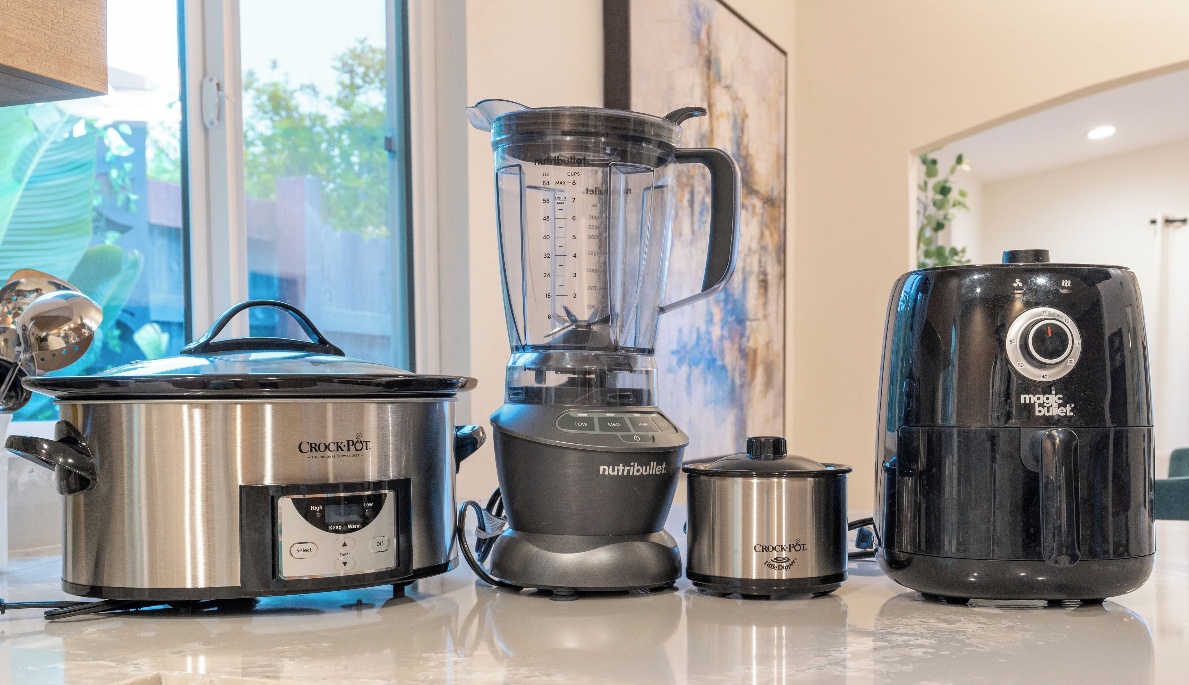Een keuken met een Crock-Pot, een Nutribullet blender en een Magic Bullet.