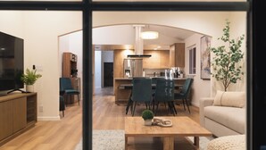 Un salon moderne comprenant un téléviseur, une table basse et un canapé. Il y a également un coin cuisine équipé d'un réfrigérateur, d'un four à micro-ondes et d'une table à manger avec des chaises.