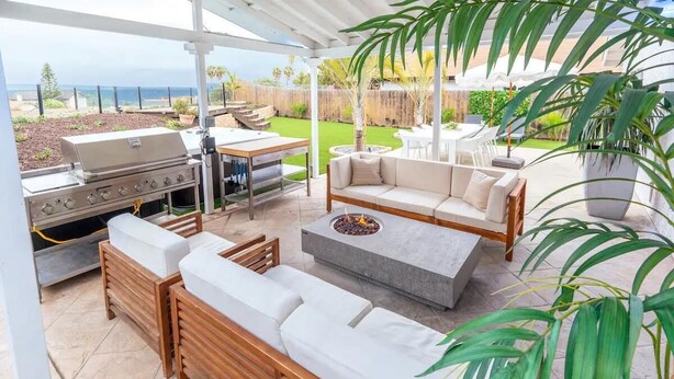 Une terrasse extérieure couverte, équipée d’un barbecue, d’un espace salon et offrant une vue sur l’océan.