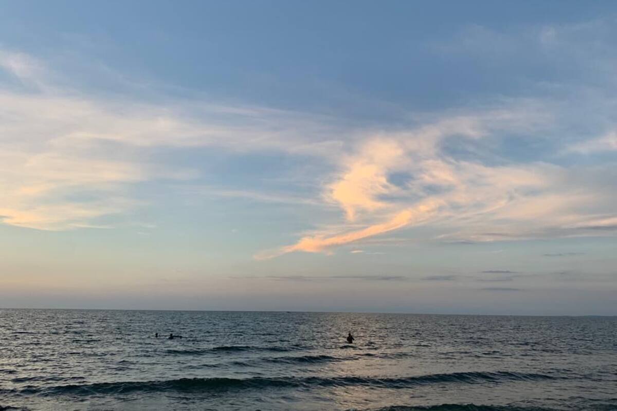 Escena de playa con aguas tranquilas y cielo despejado.
