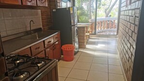 A kitchen with a gas stove, sink, and cabinets. There is a red basket on the floor and a view of a balcony with a railing. - Las acacias Tolu (Tolú)