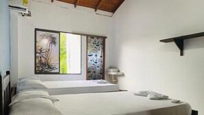 A bedroom with a bed, a nightstand, a window with a view, and a wall-mounted shelf. - Las acacias Tolu (Tolú)