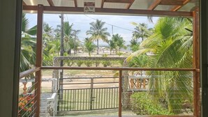 A view through a window with a metal gate and palm trees outside. - Las acacias Tolu (Tolú)