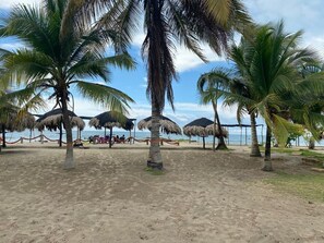 A beach with palm trees and thatched umbrellas. - Las acacias Tolu (Tolú)