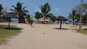 A sandy beach with palm trees and beach umbrellas. - Las acacias Tolu (Tolú)