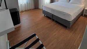 Une chambre d’hôtel moderne, dotée d’un grand lit, d’un bureau et d’une chaise.