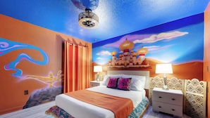 A bedroom with a large bed, two bedside tables, a nightstand, and a ceiling fan.