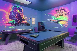 A pool table with a neon light, a pool cue rack, and a pool table with balls. - Luxury Villa,Theater,Pool,Spa,RESORT (Davenport)