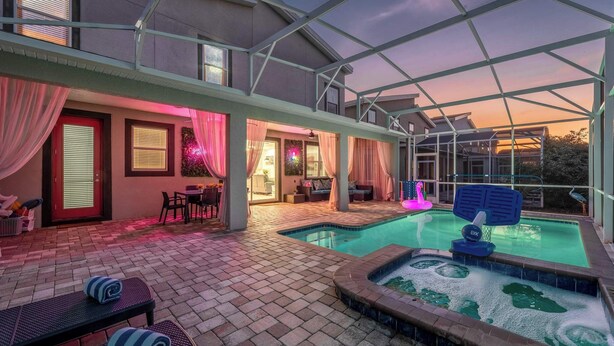 A covered outdoor area with a swimming pool, lounge chairs, and a patio with a brick floor.