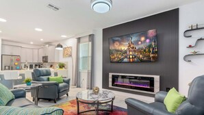 A modern living room with a fireplace, comfortable seating, and a large TV mounted on the wall.