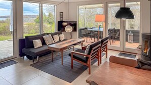 Una sala de estar moderna con sofá, mesa de comedor, sillas, televisor y chimenea.