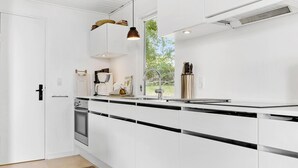 Una cocina moderna con armarios blancos, encimera negra y pileta de acero inoxidable.