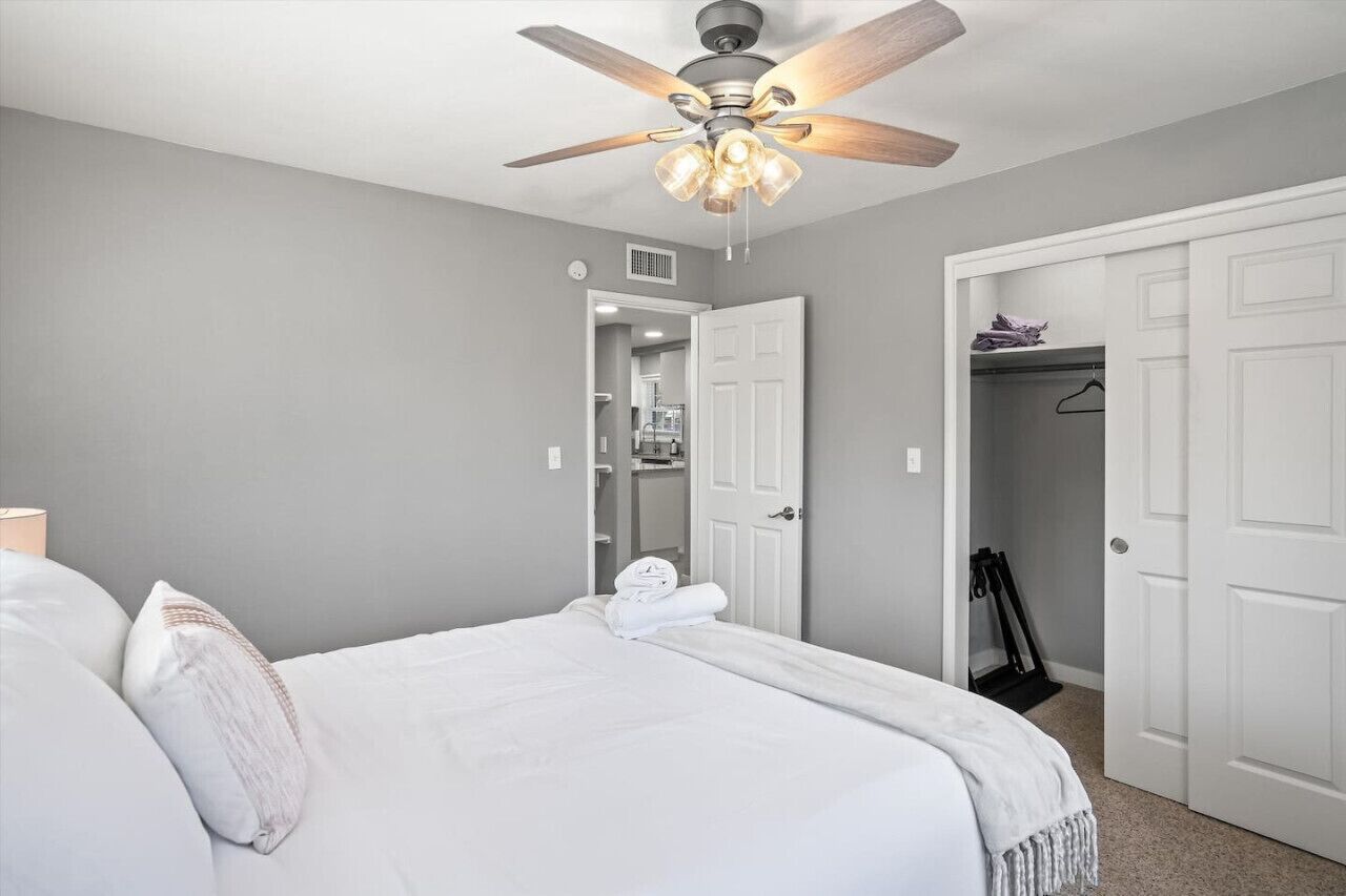 A bedroom with a bed, a ceiling fan, and a walk-in closet.