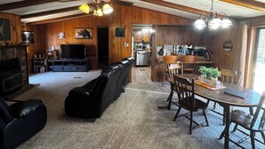 Ein geräumiger Wohnbereich mit Kamin, einem Esstisch mit Stühlen und einer Küche im Hintergrund.