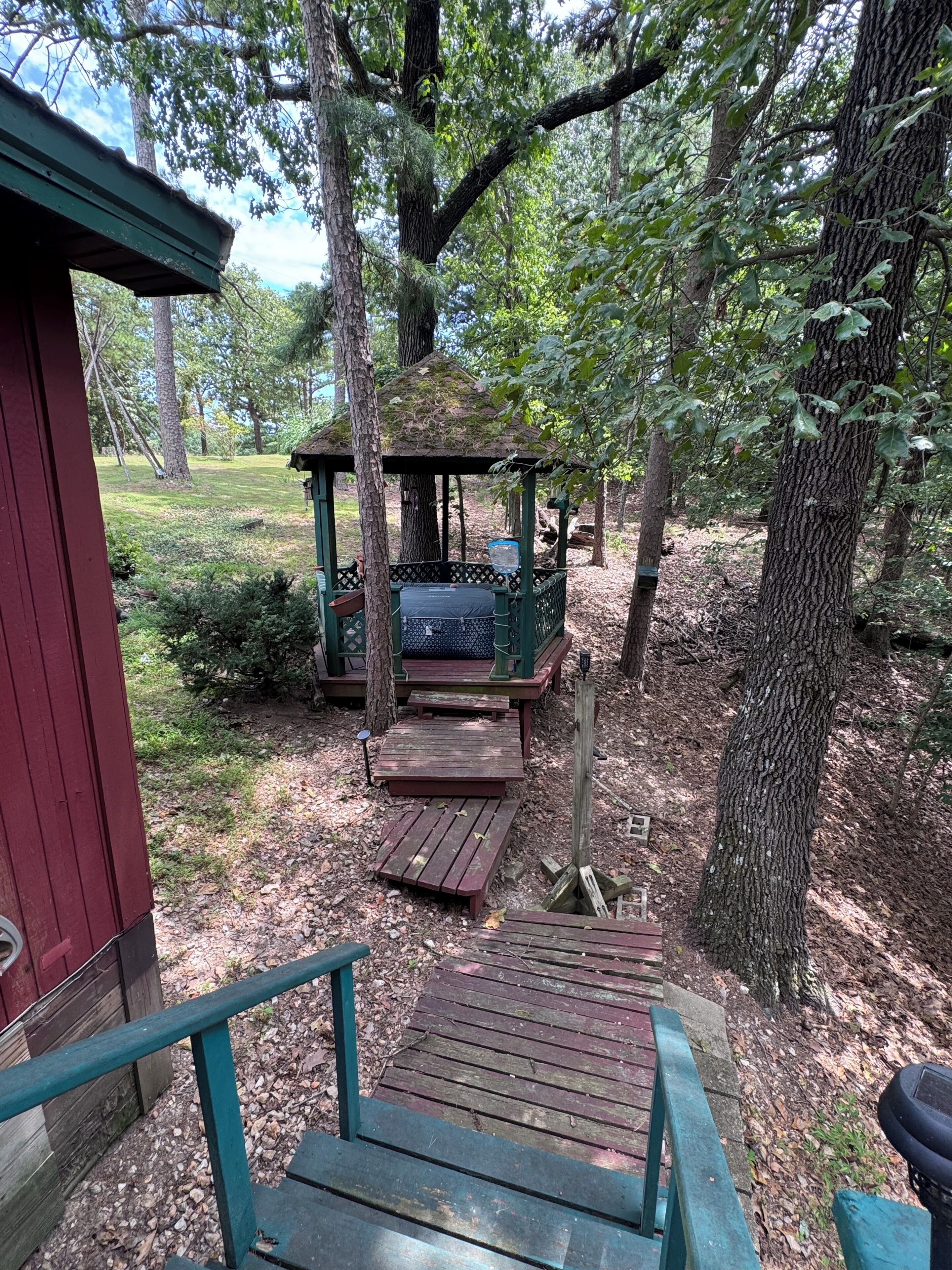 A wooden deck leading to a gazebo in a wooded area.