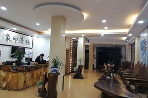 Un vestíbulo de hotel con mostrador de recepción, zona de estar y escenario.