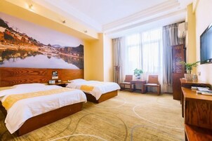 Habitación de hotel con dos camas, un escritorio, una silla, un televisor y un cuadro grande en la pared.