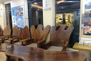 Un interior de restaurante con sillas y mesas de madera, un panel con la carta y vistas a la calle.