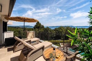 Un balcon avec des meubles en osier, une table et une bouteille d’eau.