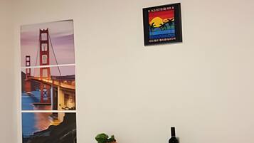 A dining area with a table set for two, a potted plant, and a poster of the Golden Gate Bridge.
