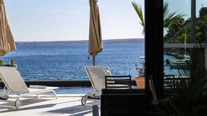 Zona junto a la piscina con sillones y sombrillas, con vistas a un lago.