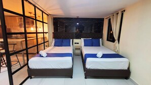 Habitación de hotel con dos camas, una mesita y vistas al cielo nocturno.
