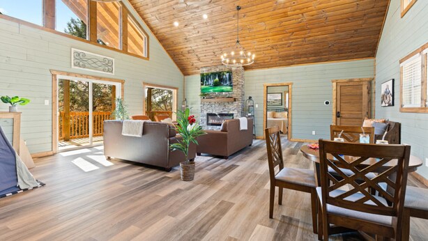 Un vaste espace de vie doté d’une cheminée, d’un plafond en bois et d’un coin repas avec des meubles en bois.