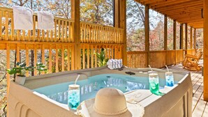 Une terrasse en bois avec un jacuzzi, des serviettes et des boissons.