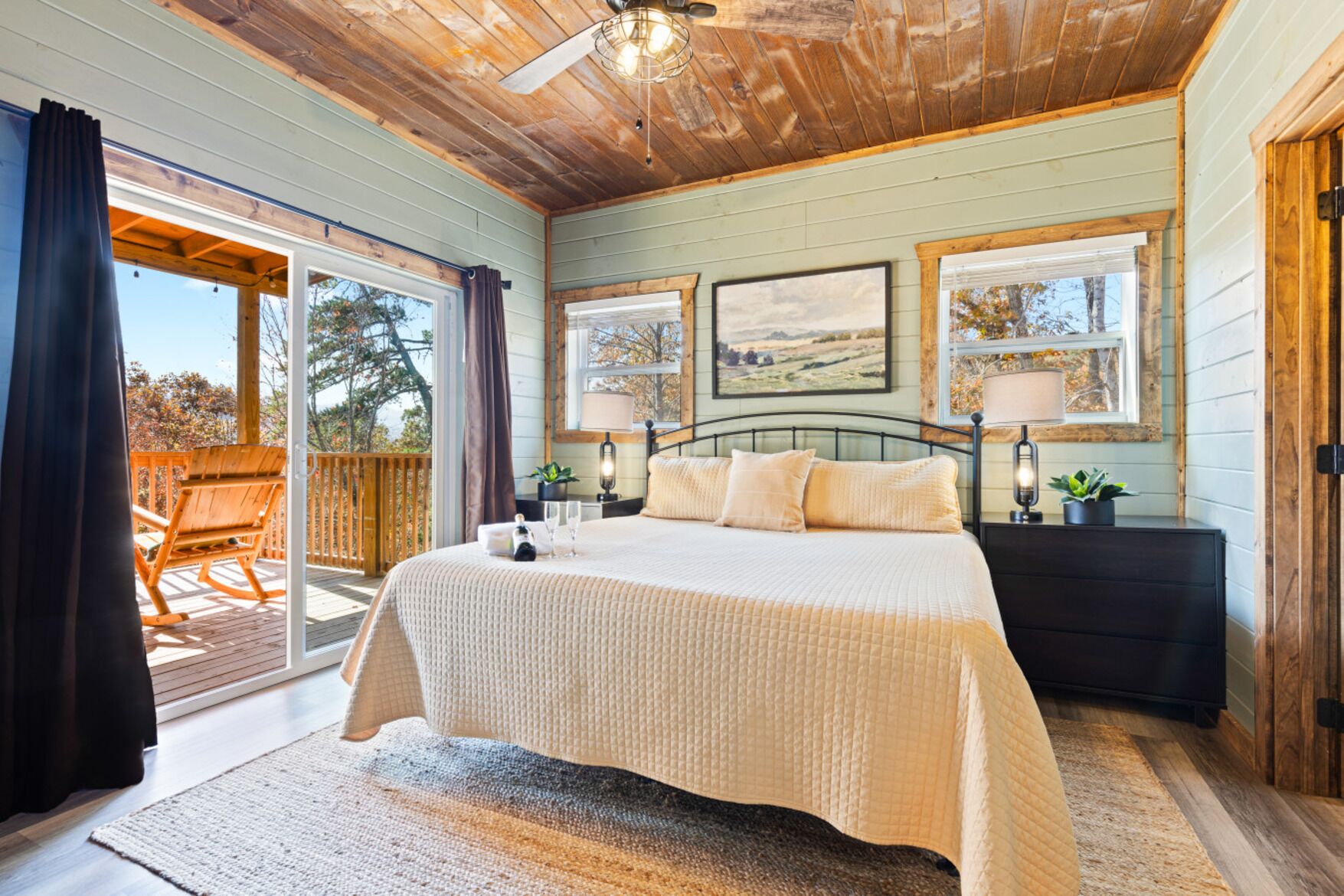 Une chambre dotée d’un grand lit, d’un plafond en bois et de deux fenêtres offrant une vue sur le paysage.