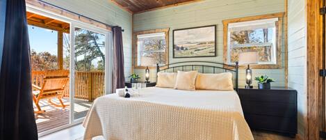 Une chambre dotée d’un grand lit, d’un plafond en bois et de deux fenêtres offrant une vue sur le paysage.