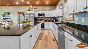 Une cuisine spacieuse avec des meubles blancs, un îlot central et un plafond en bois.