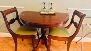 A round wooden dining table with two chairs, each with a green cushion. - Cherry's Villa 14 (Grants Pass)