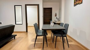 A modern dining area with a table and four chairs, a bench, and a wall-mounted artwork. - Urban Serenity: Cozy 1Bedroom apartment. (Quito)
