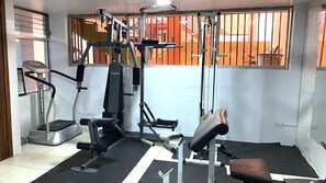 A gym with exercise equipment, a treadmill, and a bench. - Urban Serenity: Cozy 1Bedroom apartment. (Quito)