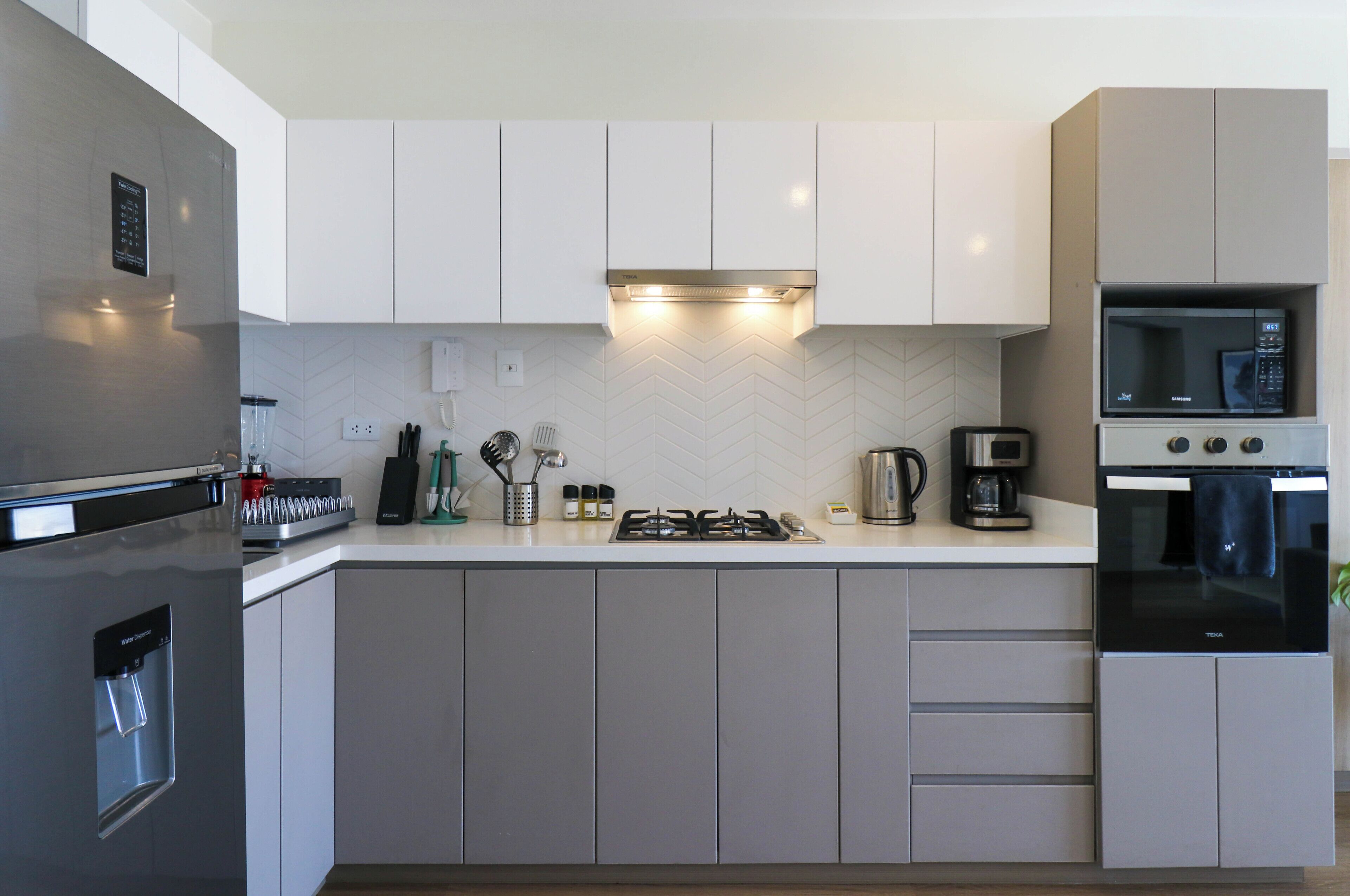 A modern kitchen with a stainless steel refrigerator, a built-in oven, a microwave, and a gas stove.