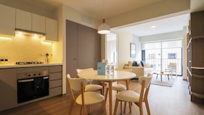 A modern kitchen with a dining area, wooden chairs, and a round table. - La Mar Miraflores by Wynwood House (Lima)