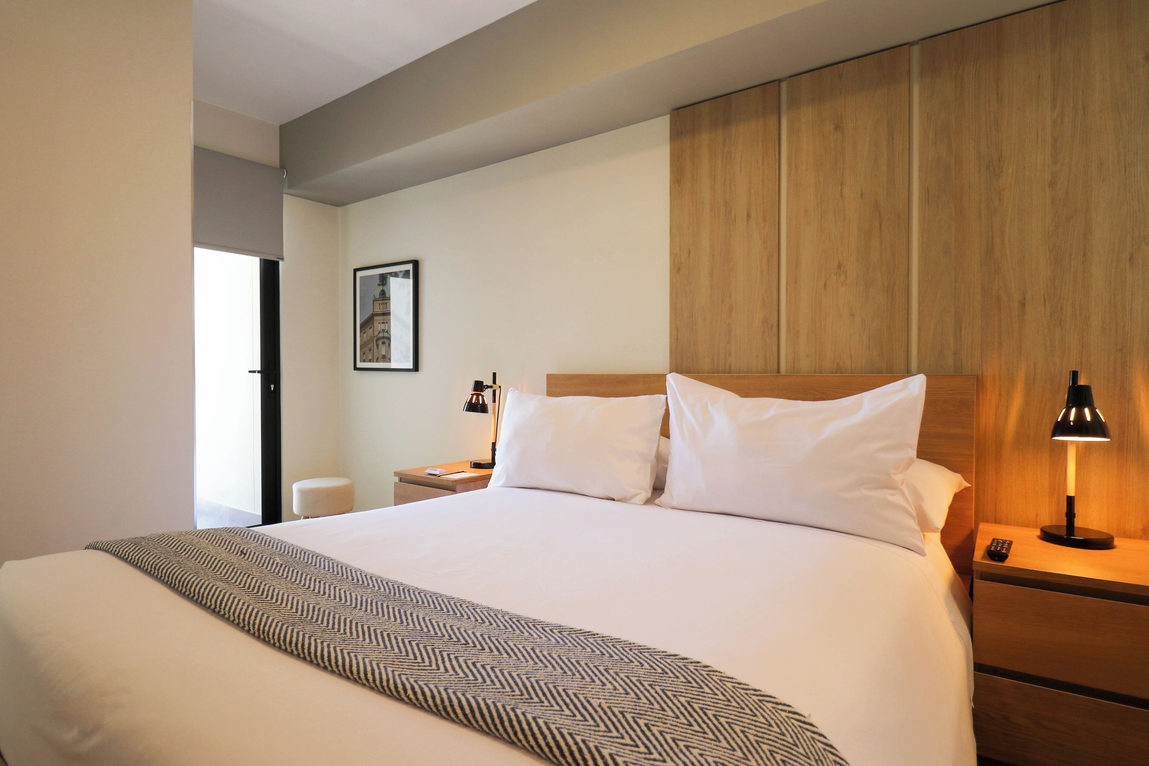 Ein Hotelzimmer mit einem großen Bett, einem Holz-Kopfteil, einem Nachttisch mit Lampe und einem gerahmten Bild an der Wand.