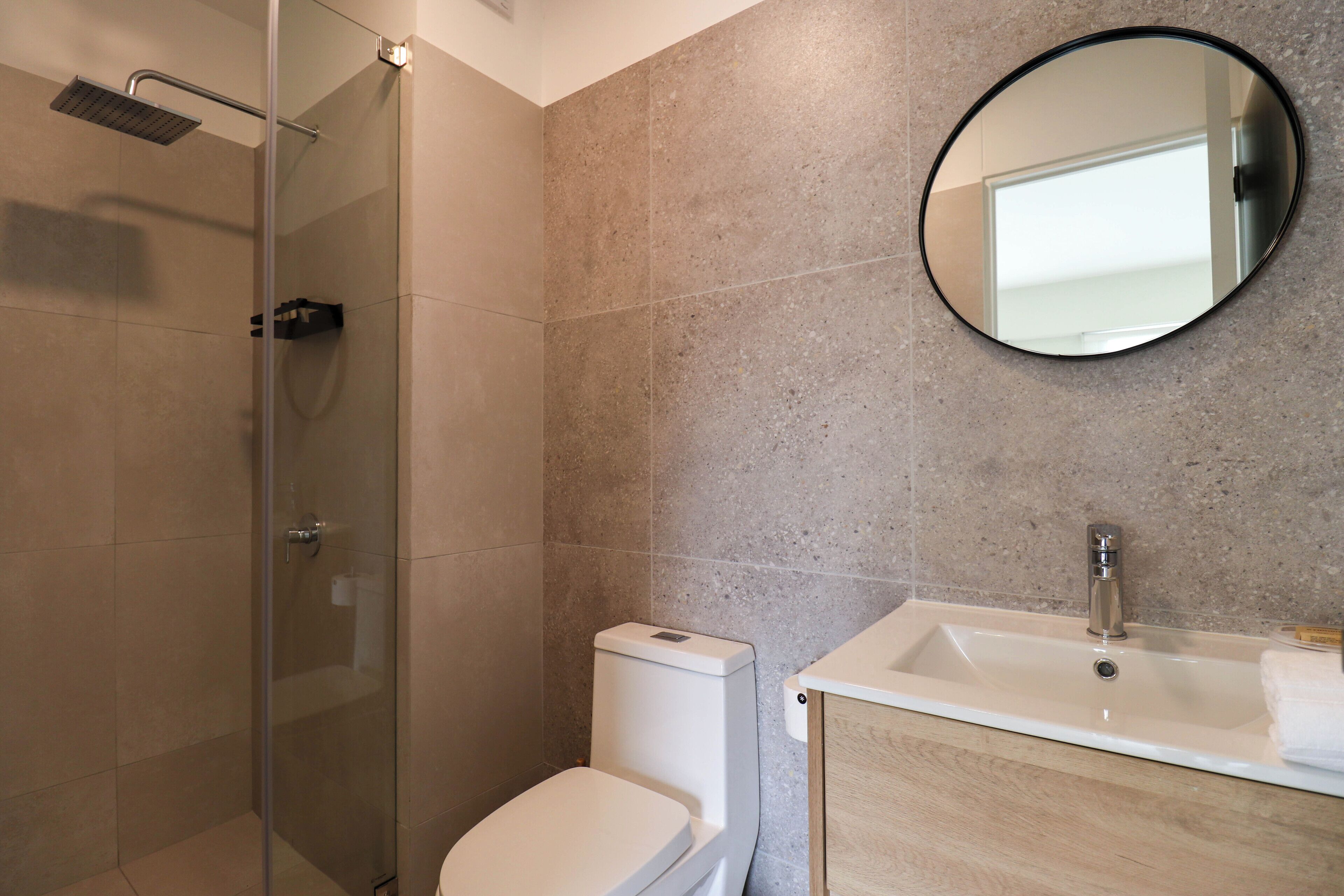 Une salle de bain avec une douche à parois de verre, des toilettes blanches et un lavabo avec un miroir au-dessus.