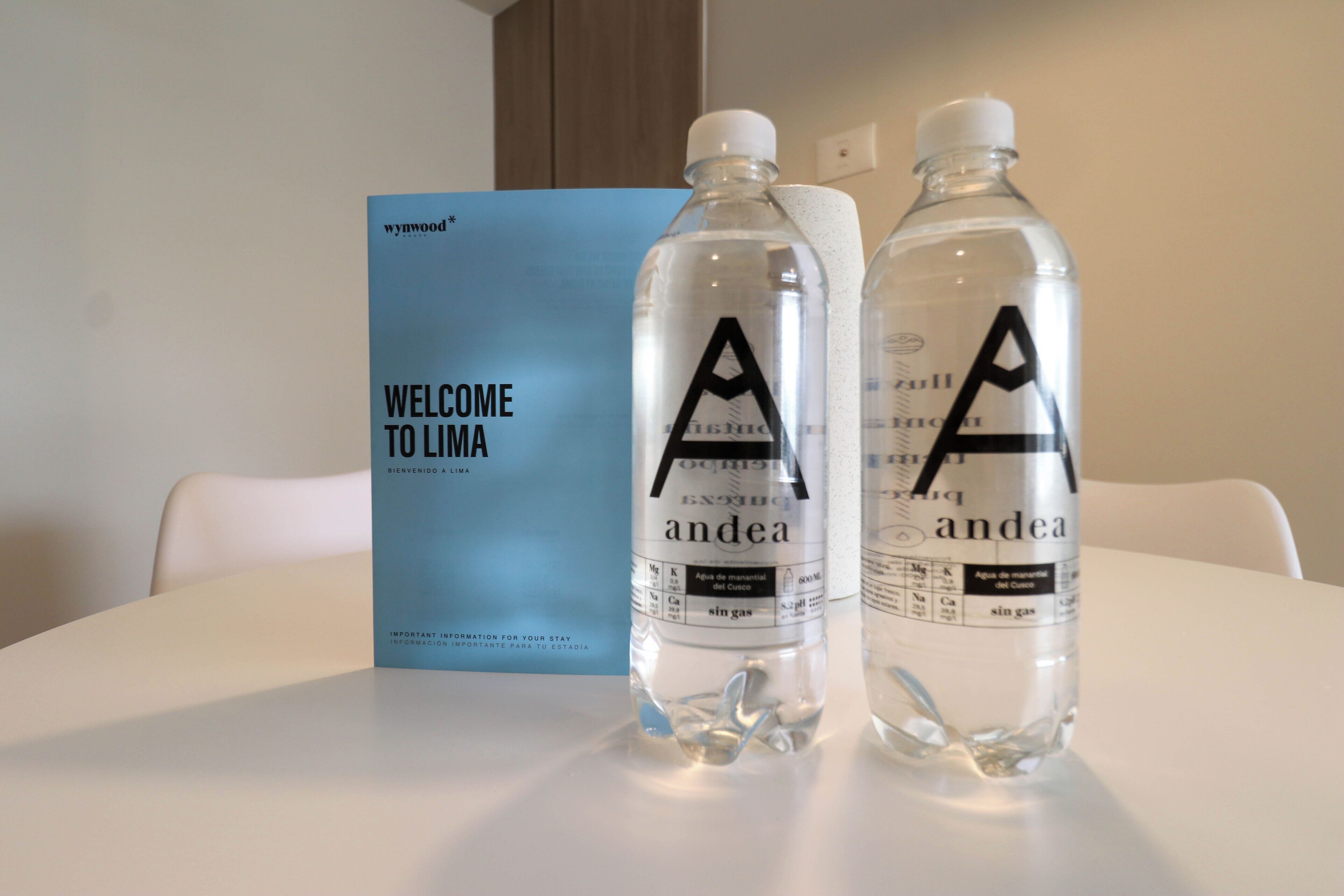 Two bottles of water labeled 'andea' on a table with a 'WELCOME TO LIMA' sign in the background.