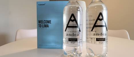 Two bottles of water labeled 'andea' on a table with a 'WELCOME TO LIMA' sign in the background.