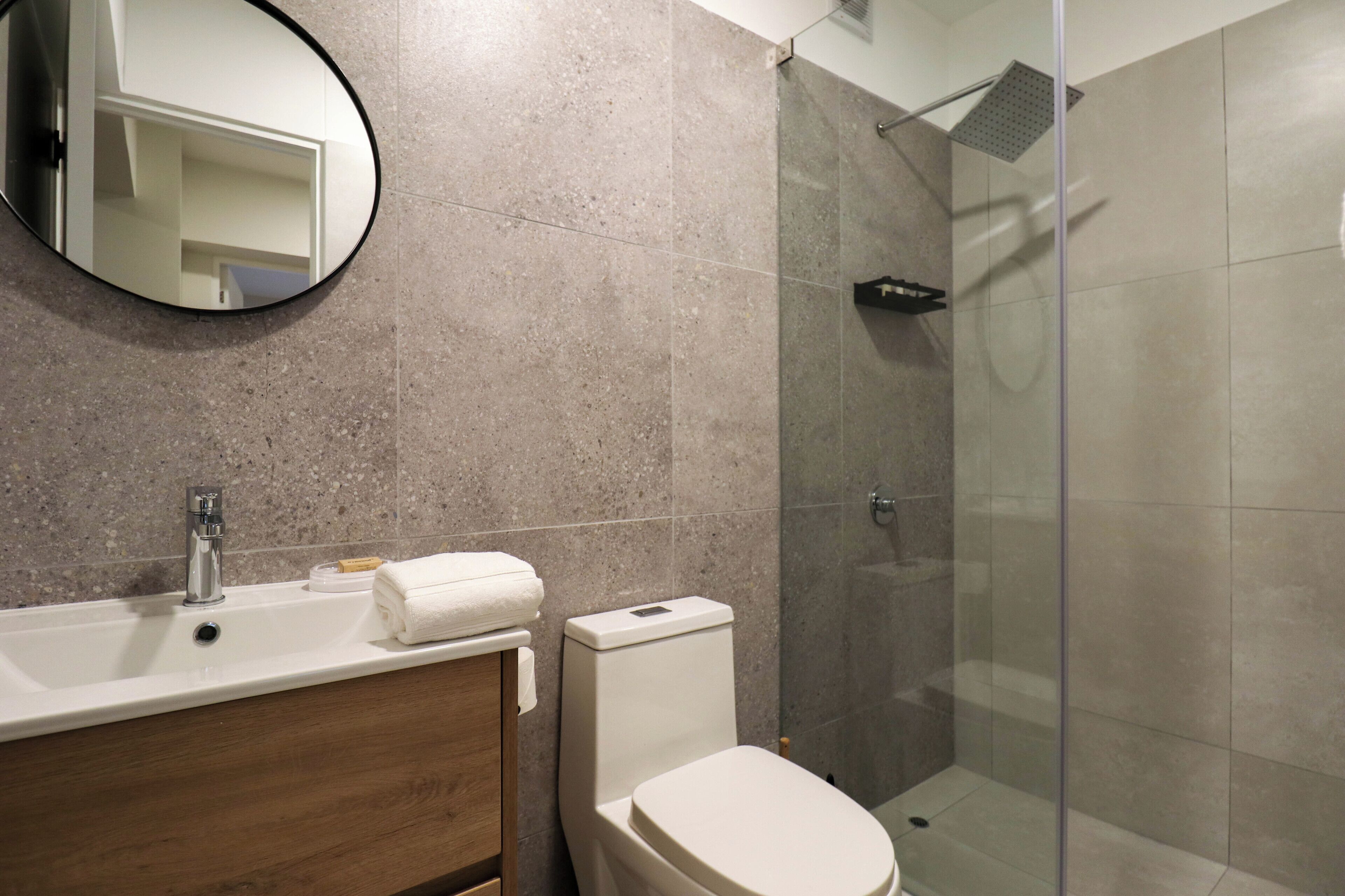Un baño moderno con lavamanos, espejo, inodoro y ducha.