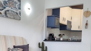 Una sala moderna con un sofá, una mesa de centro y una cocina al fondo.