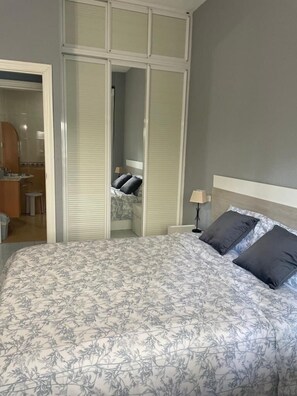 Ein Schlafzimmer mit einem Bett, einem Nachttisch, einem Spiegel und einem Kleiderschrank.