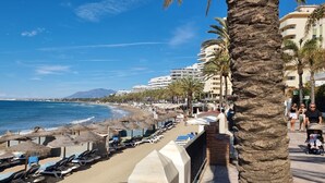 Una playa con tumbonas, sombrillas y palmeras.